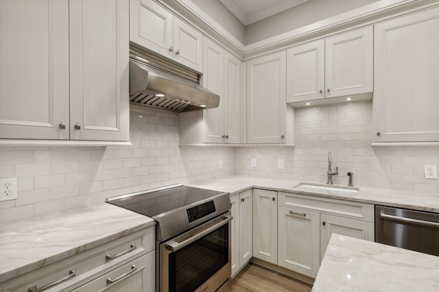 kitchen featuring appliances with stainless steel finishes, decorative backsplash, light stone countertops, range hood, and sink