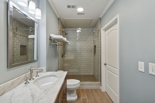 bathroom featuring toilet, a tile shower, crown molding, and vanity