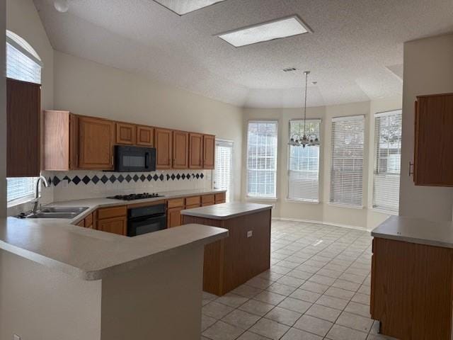 kitchen with light tile patterned flooring, sink, hanging light fixtures, a kitchen island, and black appliances