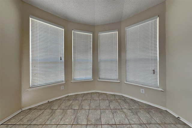 empty room with a textured ceiling and light tile patterned flooring