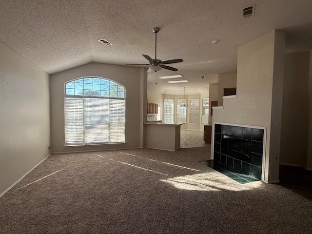 unfurnished living room with a tiled fireplace, lofted ceiling, ceiling fan, and dark colored carpet