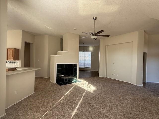 unfurnished living room with dark colored carpet, a tile fireplace, a textured ceiling, and ceiling fan