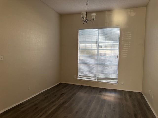 unfurnished room featuring dark wood-type flooring and a chandelier