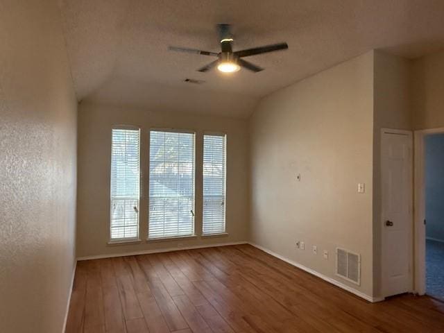 spare room featuring wood-type flooring, lofted ceiling, a textured ceiling, and ceiling fan