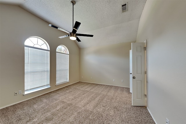 carpeted empty room featuring vaulted ceiling, ceiling fan, and a textured ceiling