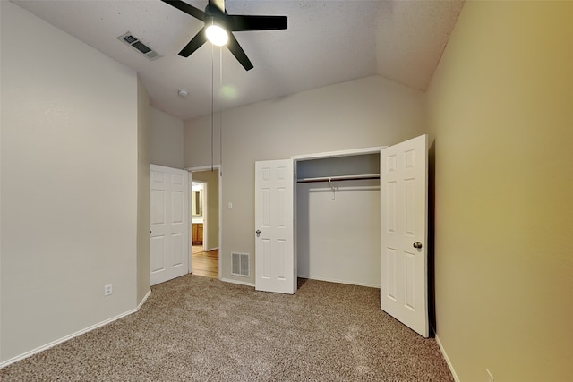 unfurnished bedroom with ceiling fan, a closet, lofted ceiling, and carpet