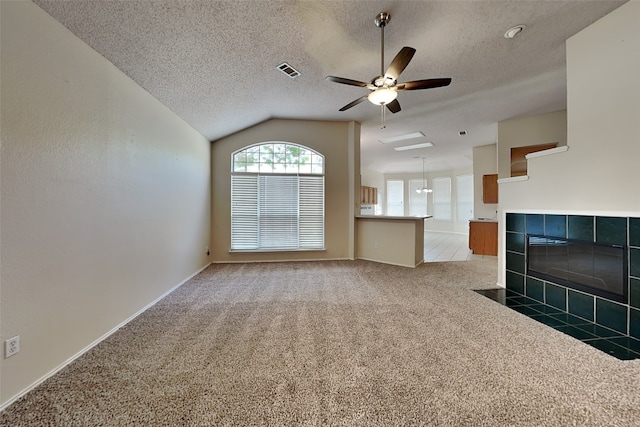 unfurnished living room with vaulted ceiling, a fireplace, carpet flooring, ceiling fan, and a textured ceiling