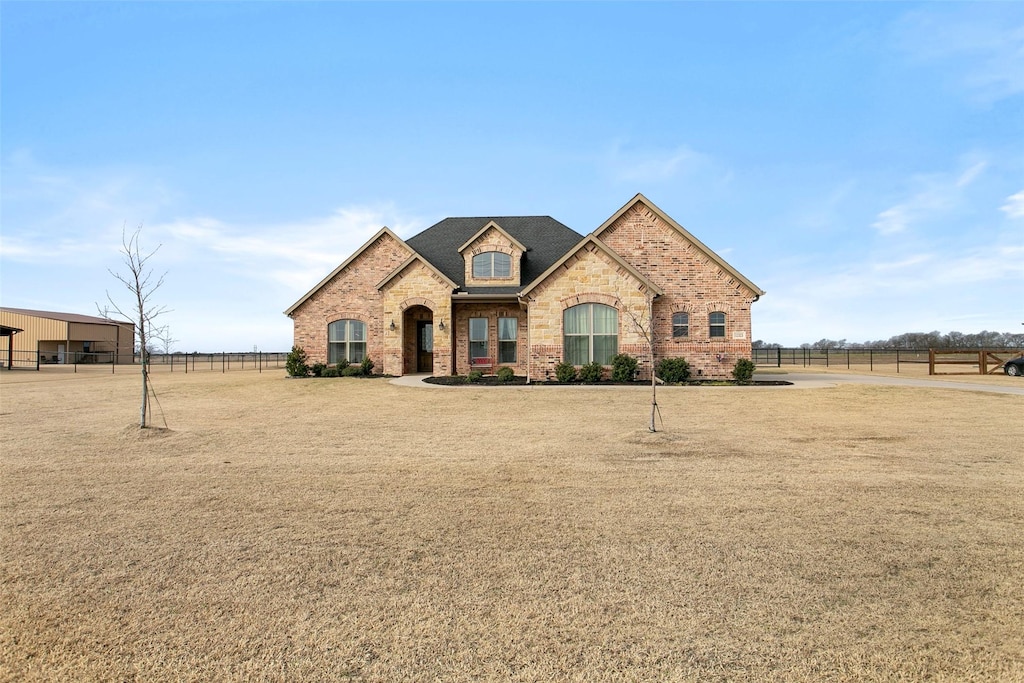 french country inspired facade featuring a front yard and a rural view