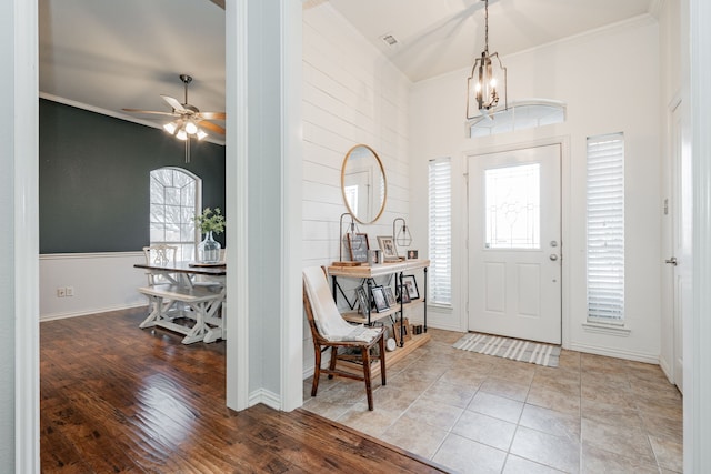 foyer entrance featuring crown molding, ceiling fan with notable chandelier, and wood-type flooring