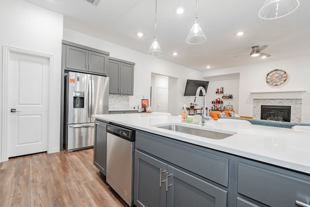 kitchen featuring sink, light hardwood / wood-style flooring, appliances with stainless steel finishes, gray cabinetry, and hanging light fixtures