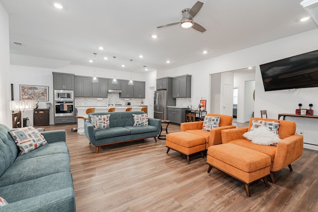 living room featuring ceiling fan and light hardwood / wood-style floors