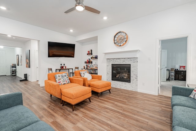 living room with ceiling fan, a fireplace, and light hardwood / wood-style floors