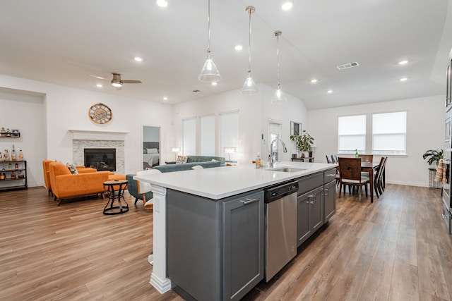 kitchen featuring gray cabinetry, pendant lighting, stainless steel dishwasher, and a center island with sink