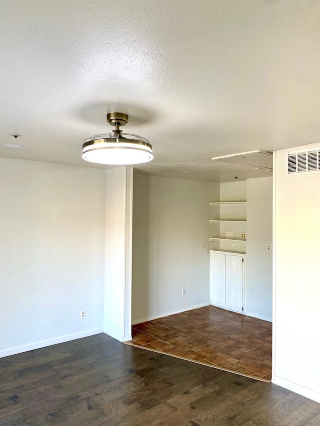 unfurnished room featuring a textured ceiling and dark wood-type flooring