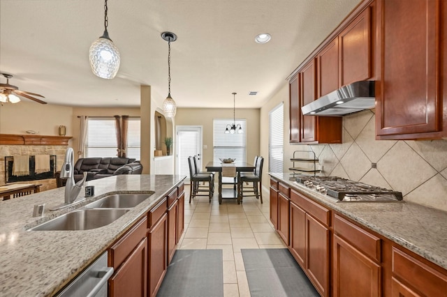 kitchen featuring decorative backsplash, light stone counters, pendant lighting, and sink