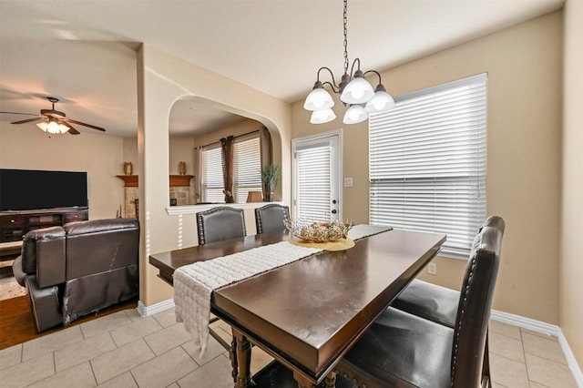 dining space with ceiling fan with notable chandelier and light tile patterned flooring