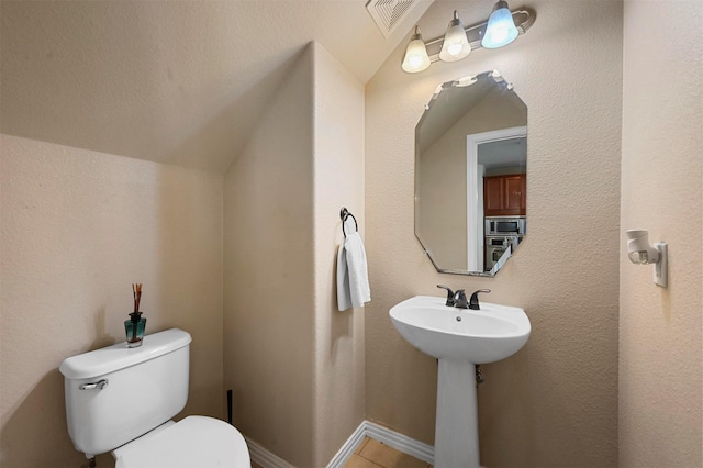 bathroom featuring lofted ceiling and toilet