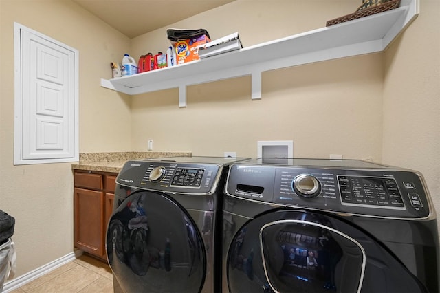 laundry room featuring cabinets, light tile patterned floors, and washer and clothes dryer