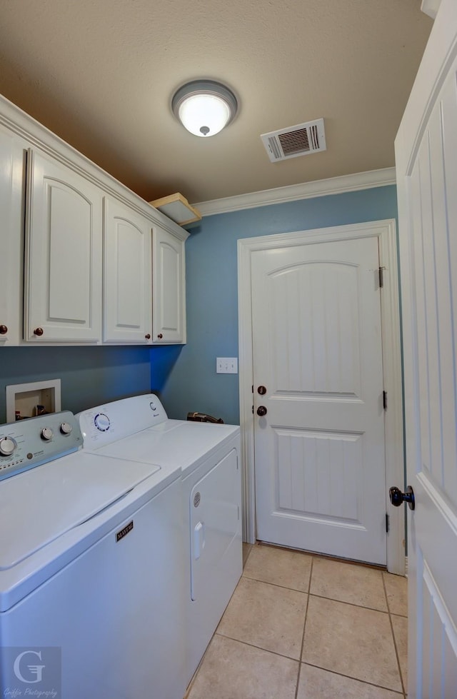 washroom with light tile patterned flooring, separate washer and dryer, ornamental molding, and cabinets