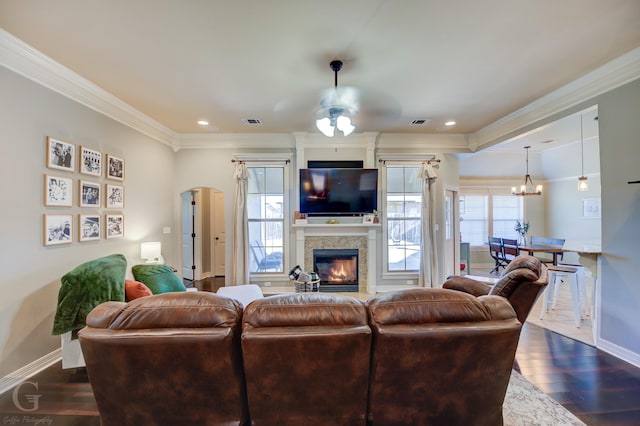 living room featuring ceiling fan with notable chandelier, dark wood-type flooring, and crown molding