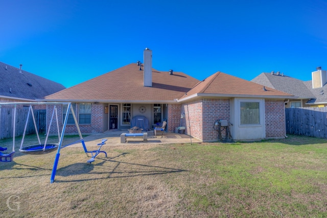 rear view of property with a playground, a patio area, a lawn, and a trampoline