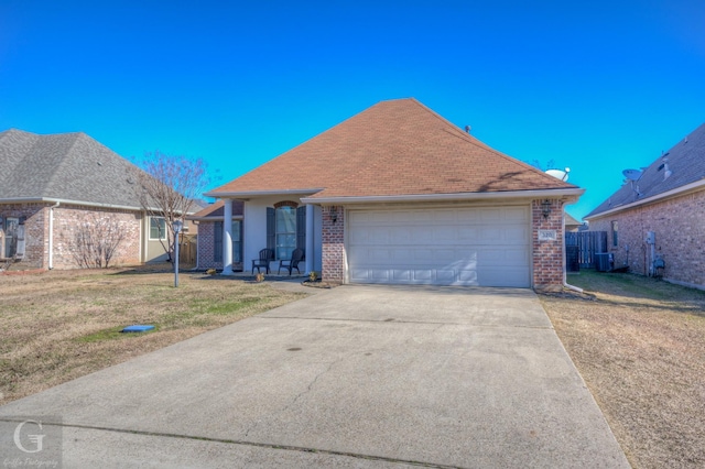 view of front of home with a garage, cooling unit, and a front lawn