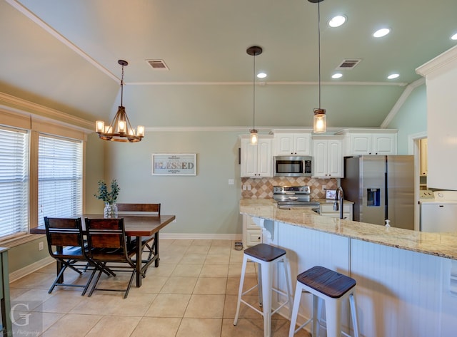 kitchen with light stone countertops, white cabinets, appliances with stainless steel finishes, washer / clothes dryer, and vaulted ceiling