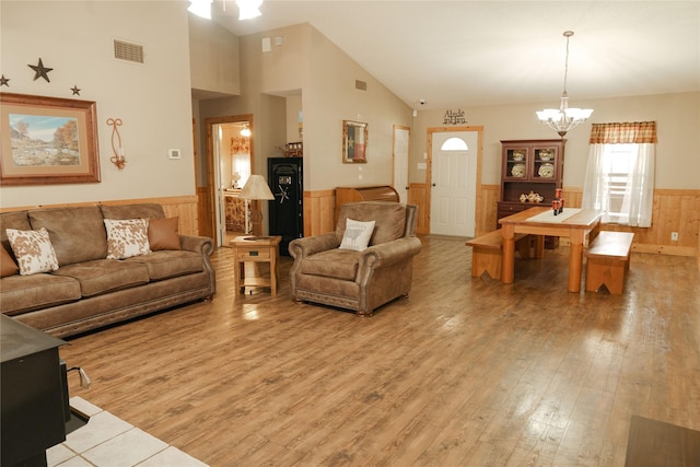 living room with light wood-type flooring, vaulted ceiling, and an inviting chandelier