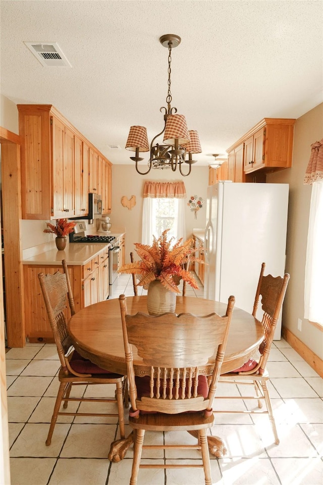 dining room with a notable chandelier, light tile patterned flooring, and a textured ceiling