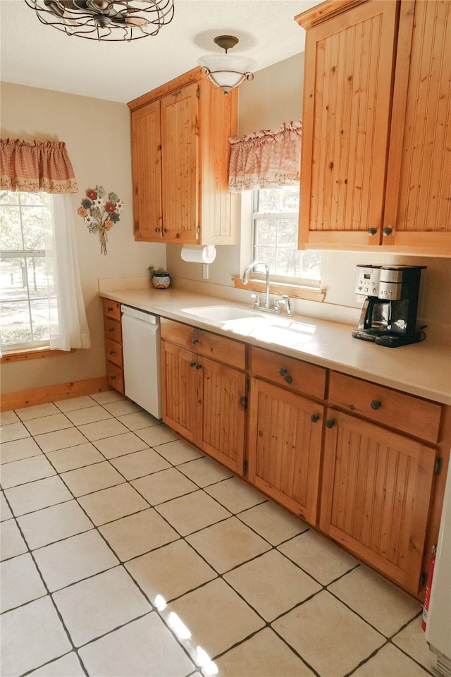 kitchen with white dishwasher, sink, plenty of natural light, and light tile patterned flooring