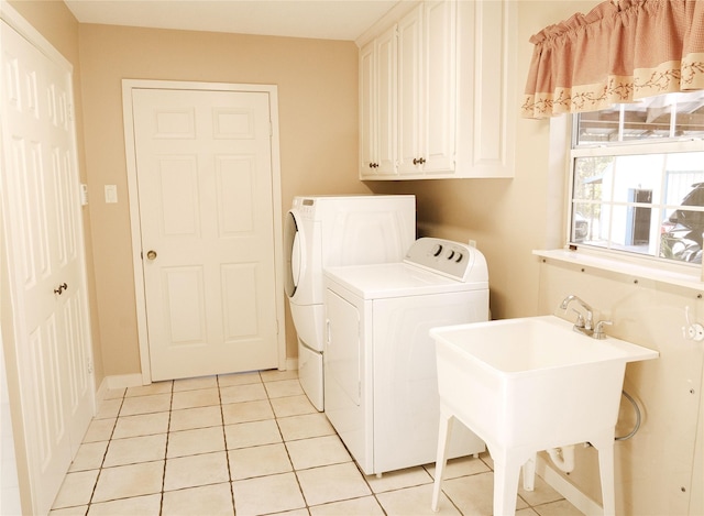 clothes washing area with cabinets, light tile patterned floors, washer and clothes dryer, and sink