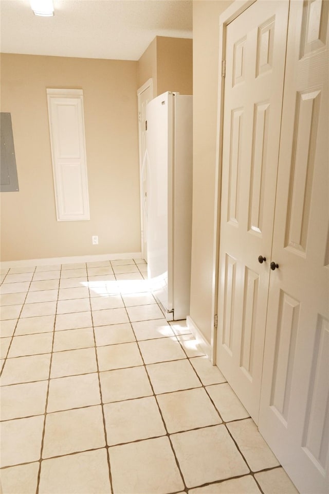 hall with light tile patterned flooring and electric panel