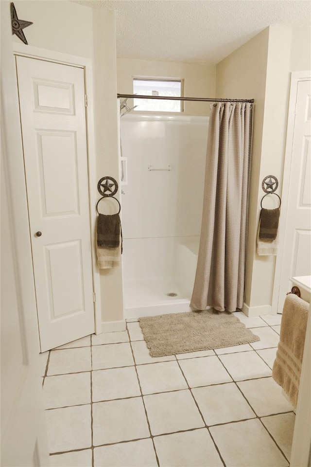 bathroom with a textured ceiling, a shower with shower curtain, and tile patterned floors