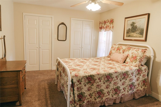 bedroom featuring multiple closets, dark carpet, and ceiling fan