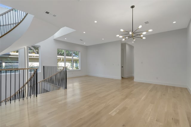 unfurnished room featuring light wood-type flooring, a notable chandelier, and vaulted ceiling