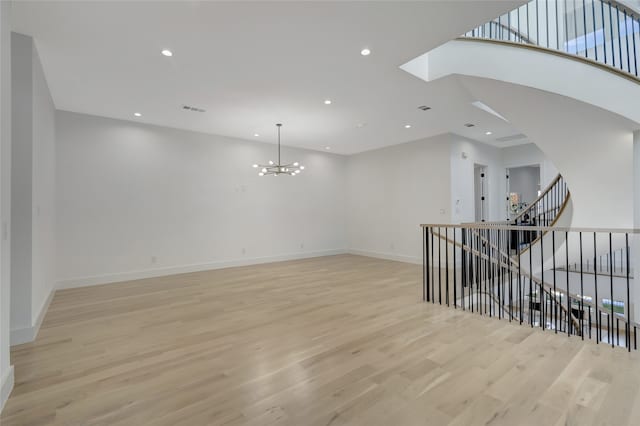 empty room with a chandelier and light hardwood / wood-style flooring