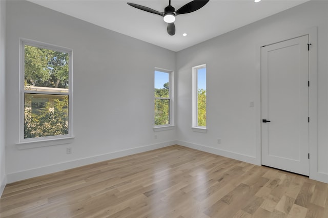 spare room featuring light wood-type flooring, ceiling fan, and a wealth of natural light