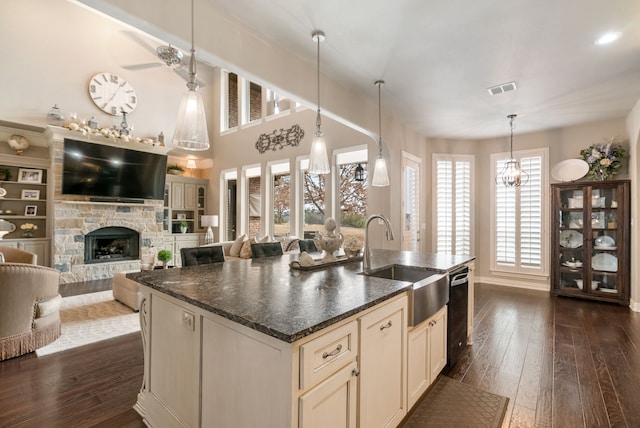 kitchen with a center island with sink, black dishwasher, dark hardwood / wood-style floors, a fireplace, and sink