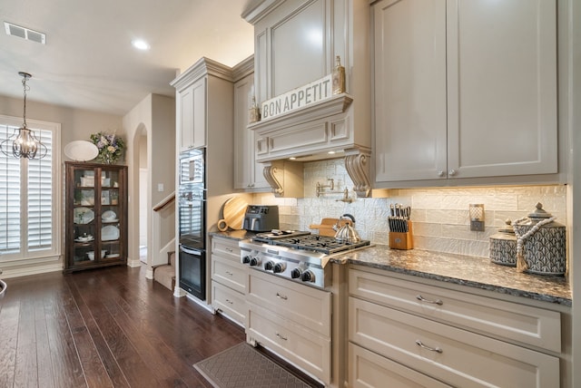 kitchen with pendant lighting, stainless steel appliances, backsplash, dark hardwood / wood-style floors, and light stone counters