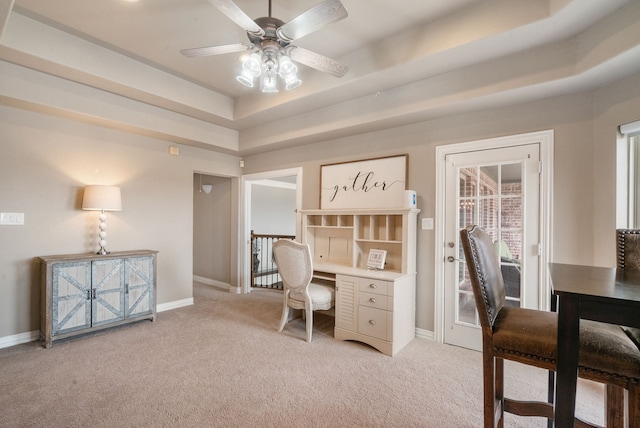 office with a raised ceiling, light colored carpet, and ceiling fan