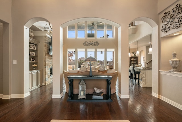 interior space featuring a high ceiling, dark hardwood / wood-style flooring, and a stone fireplace