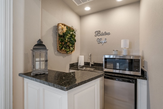 1901 Yucatan Dr, Granbury, TX 76048 - kitchen with stainless steel microwave, a sink, dishwasher, white cabinetry, and recessed lighting