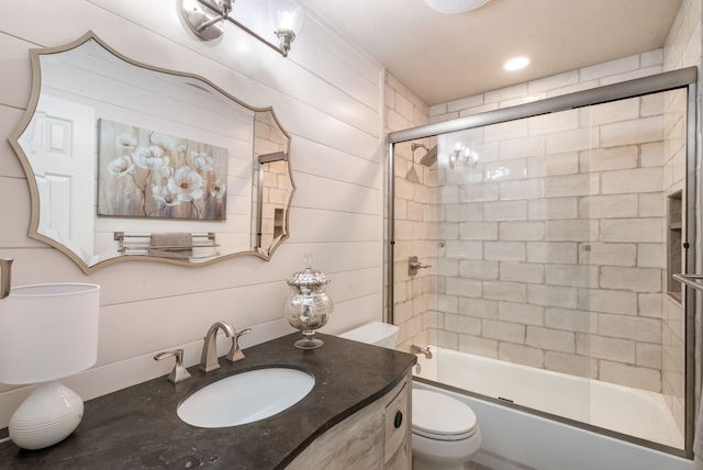 full bathroom with combined bath / shower with glass door, vanity, and toilet