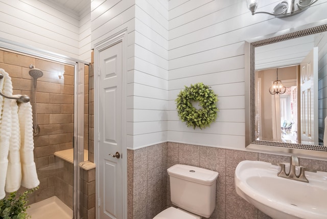 bathroom with sink, toilet, an enclosed shower, and wooden walls