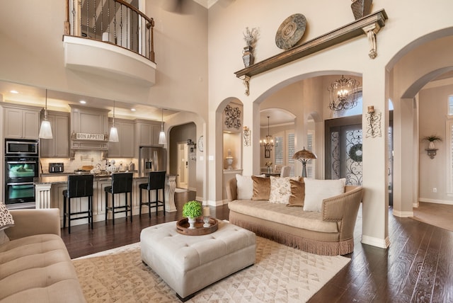 living room featuring an inviting chandelier, dark hardwood / wood-style flooring, and a towering ceiling