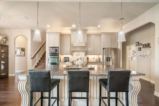 kitchen featuring appliances with stainless steel finishes, a large island, dark stone counters, and tasteful backsplash