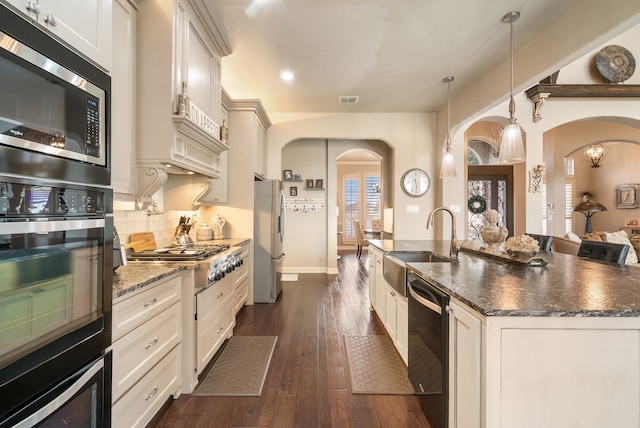 kitchen featuring black appliances, a kitchen bar, dark stone counters, sink, and hanging light fixtures