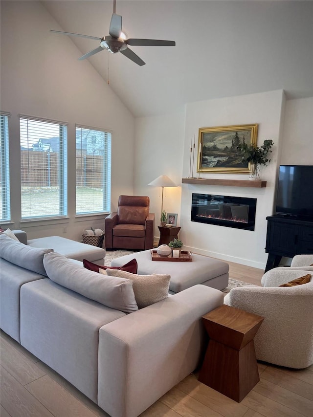 living room with ceiling fan, vaulted ceiling, and light wood-type flooring