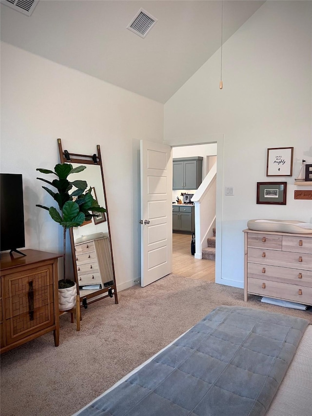 carpeted bedroom with high vaulted ceiling