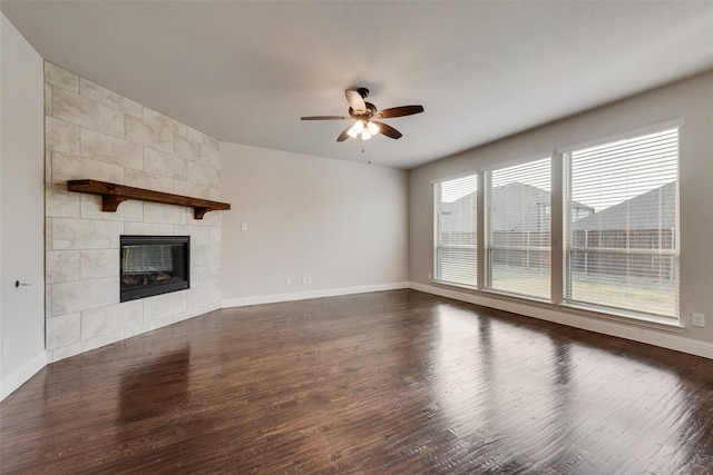 unfurnished living room featuring a tile fireplace, dark hardwood / wood-style floors, and ceiling fan